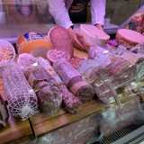 Davanti a noi il bancone espone in bella vista mortadella, fesa di tacchino, speck, bresaola e salame